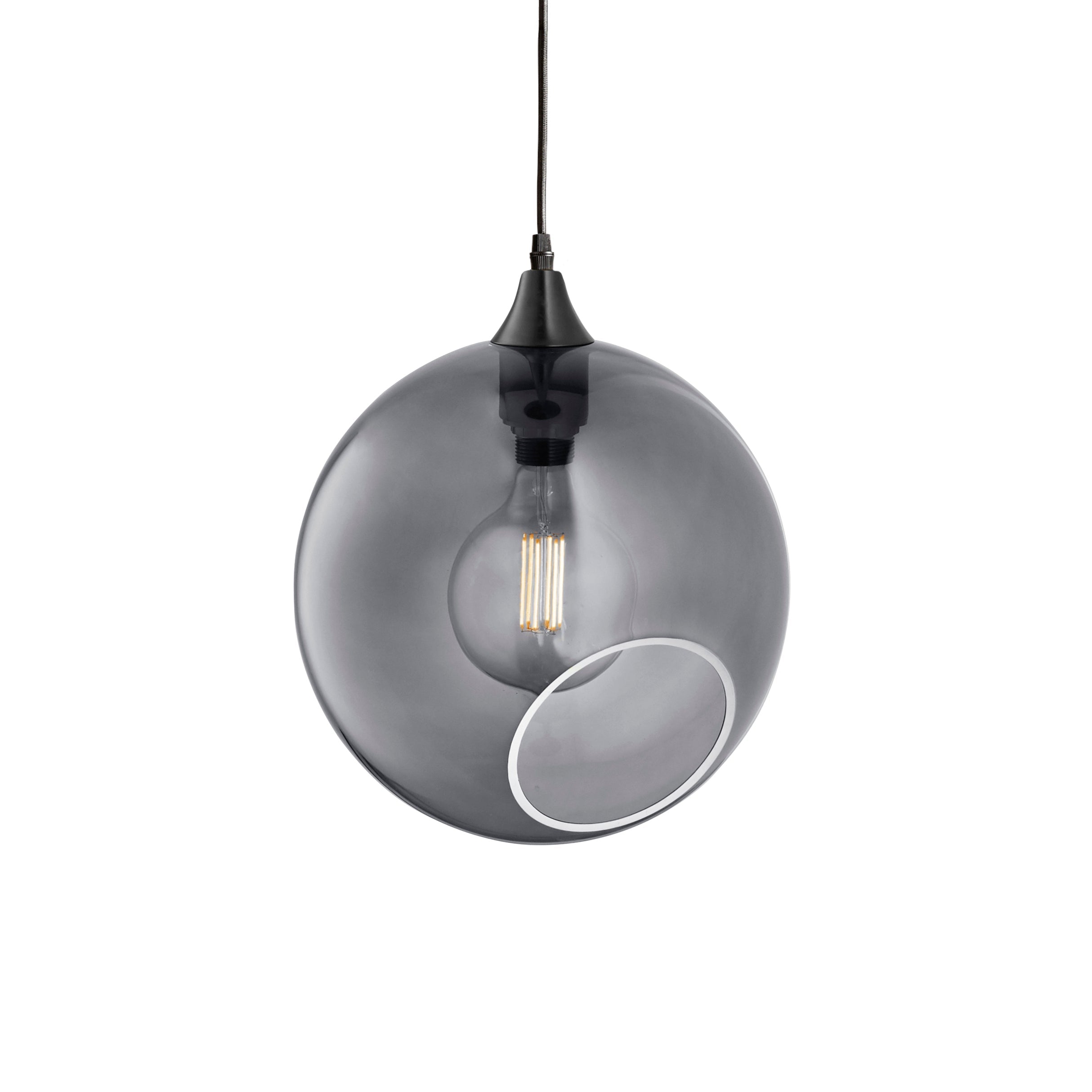 Rund lampa i rökfärgat glas och med en avskuren bit som ger en skymt av glödlampan. Sockeln och rosetten är svarta och kabeln av svart textil.