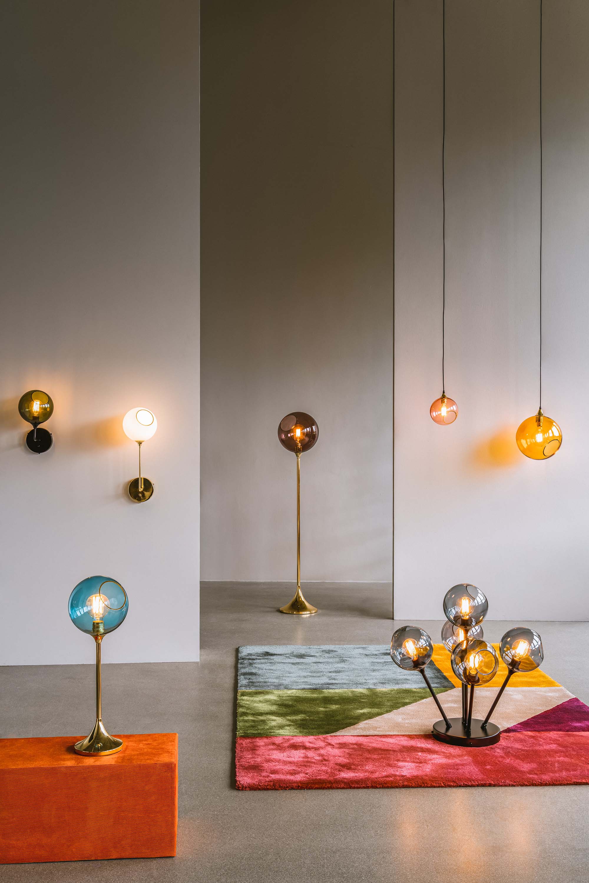 Rund lampa i rosafärgat glas med en avskuren bit med guldkant. Sockeln är guldfärgad och kabeln av svart textil.