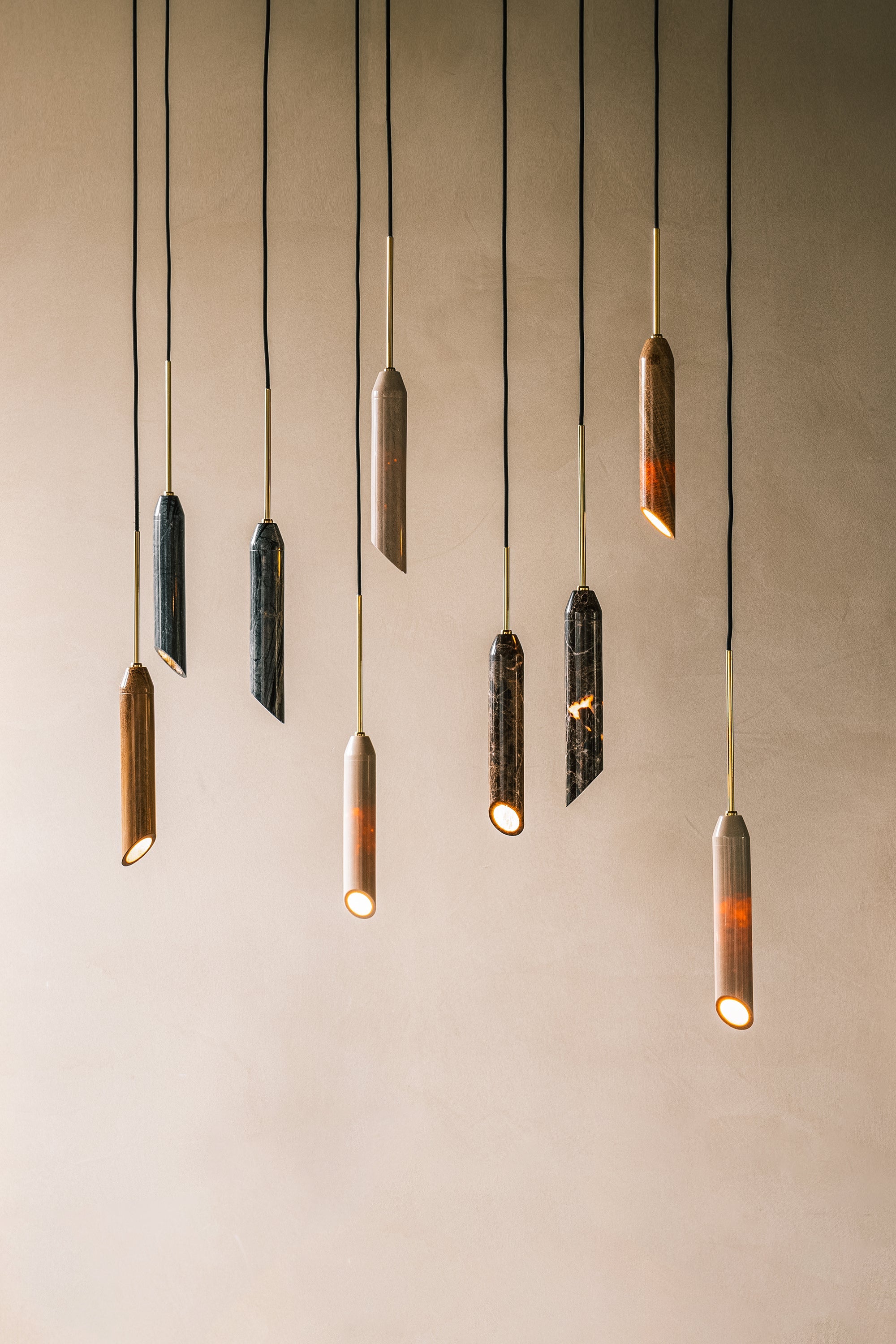 Pendellampa i svart marmor med diagonalt snitt och med guldfärgade detaljer. Lampan har en svart textilkabel.