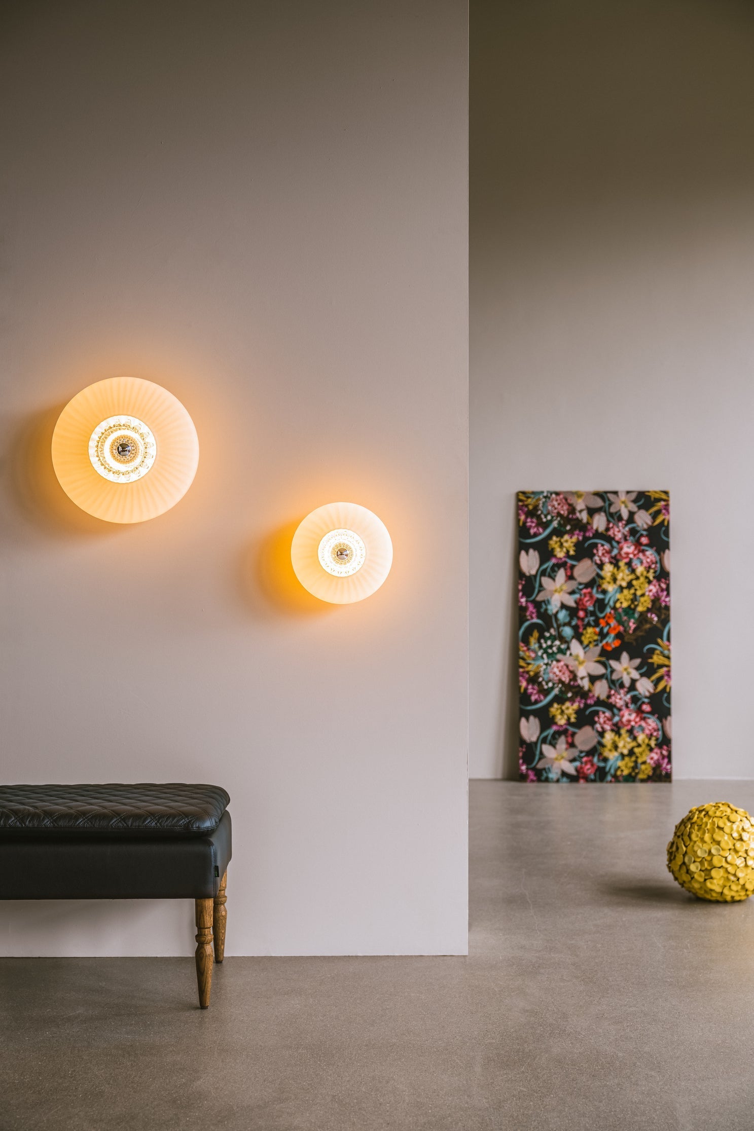 Rund vägglampa i veckat glas i färgen amber som skapar ett ljusspel på väggen.