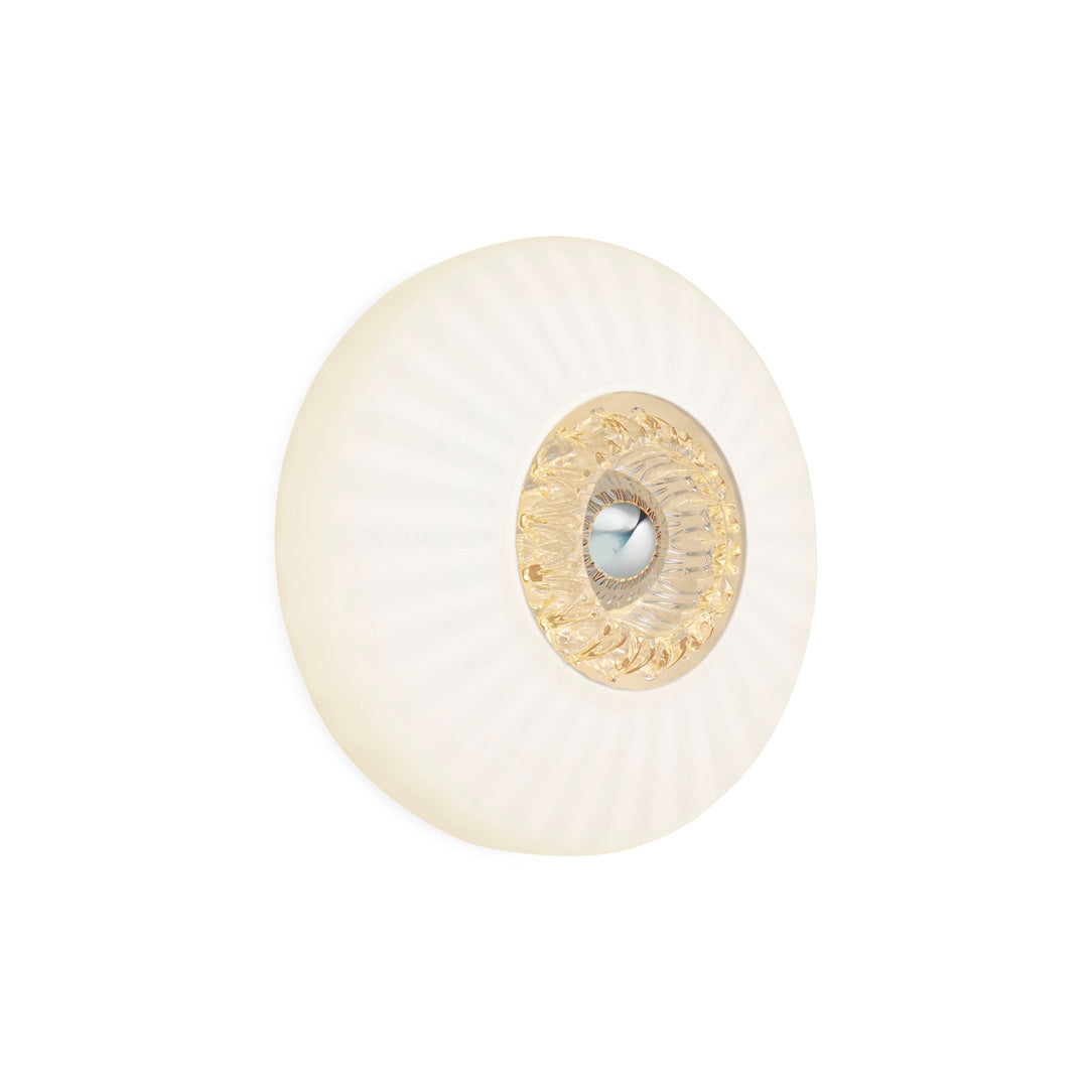 Rund vägglampa i opalfärgat veckat glas som skapar ett ljusspel på väggen.