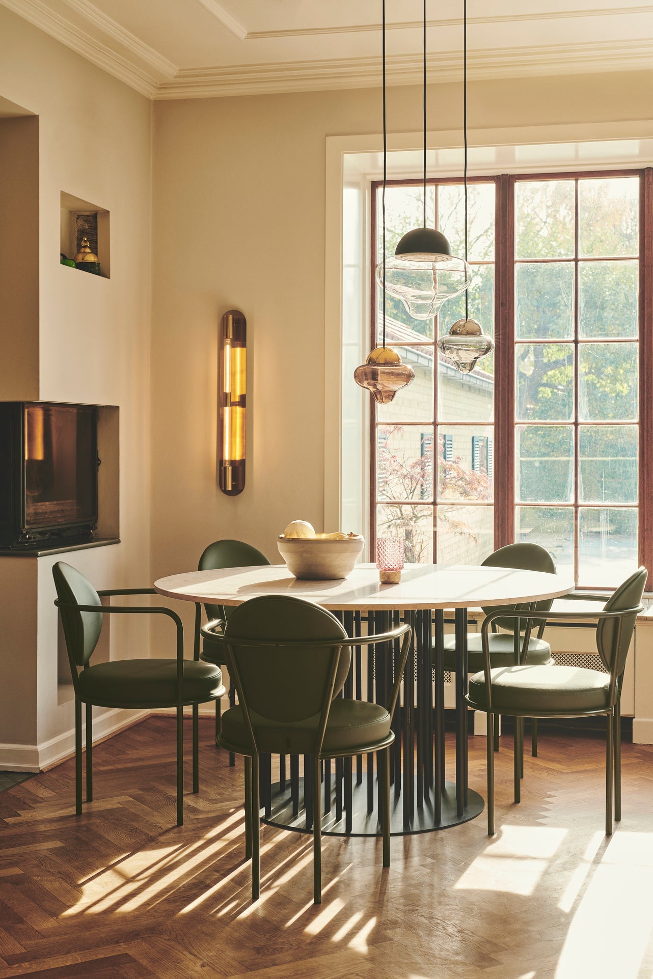 En stor och två små Nutty Clear pendellampor som hänger över ett matbord.