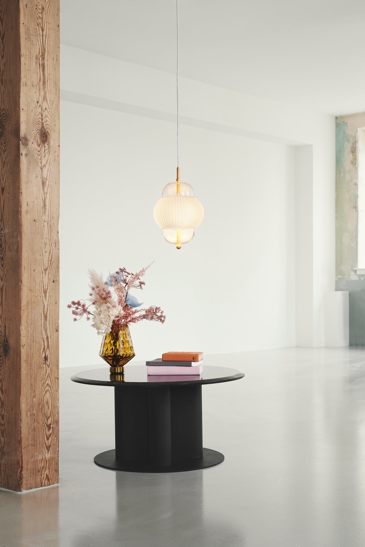 Lampa i klarglas och matt vitt veckat glas. Dessutom har lampan detaljer i mässing och en vit textilkabel.