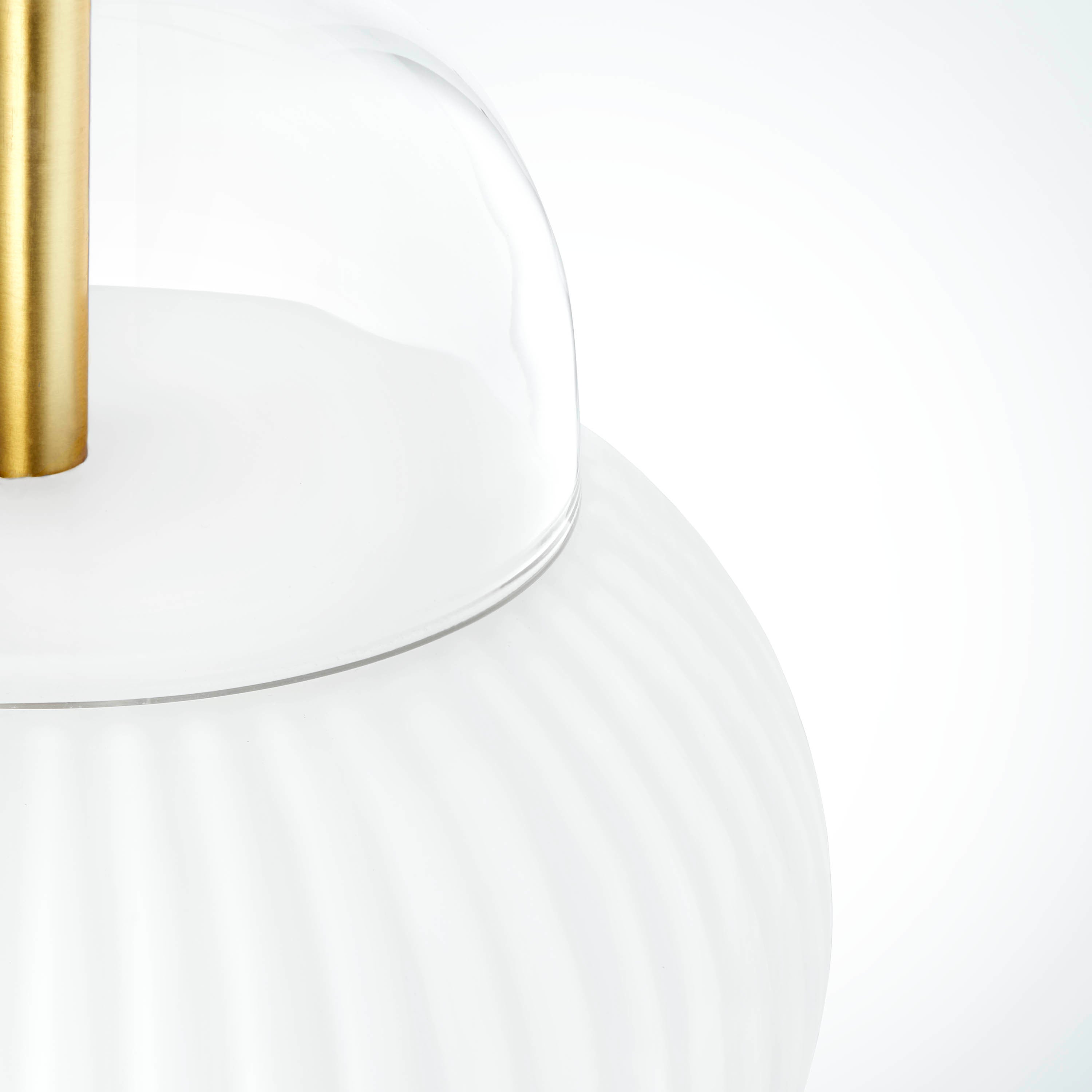 Lampa i klarglas och matt vitt veckat glas. Dessutom har lampan detaljer i mässing och en vit textilkabel.