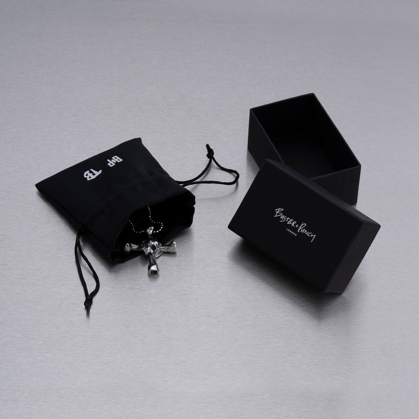 Kartong som innehåller halsband med hänge i form av en dödskalle som samtidigt är en trumnyckel, i stål.