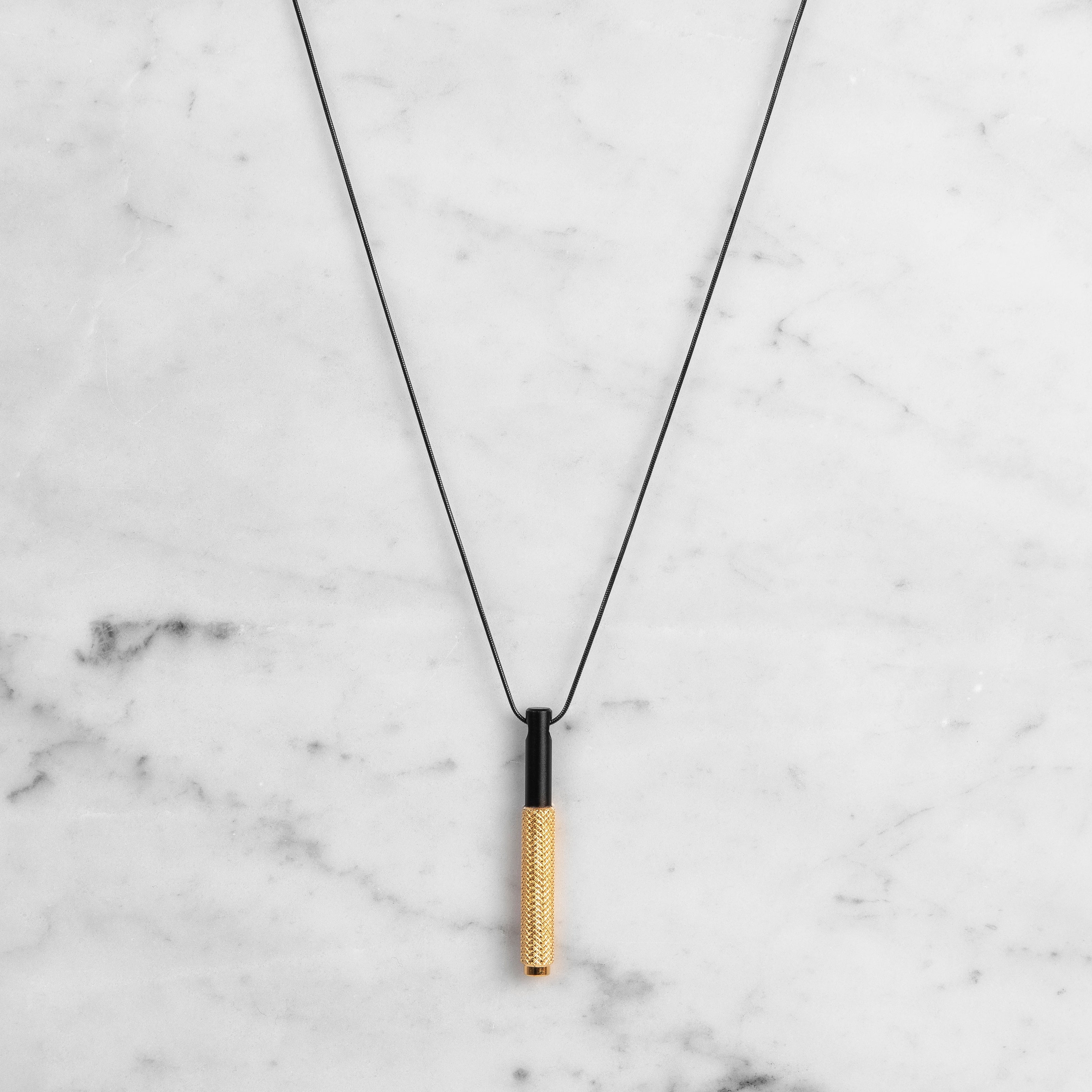 Halsband i svart med hänge i svart och mässing. Mässingsdelen av hänget är dekorerat med det populära diamantslipade mönstret.