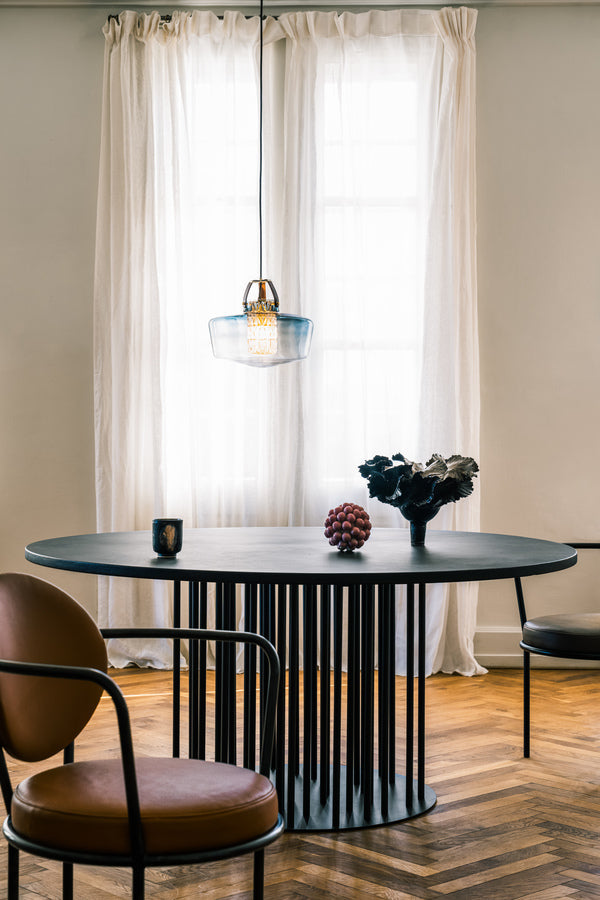 Lampan har en rökfärgad glasskärm i munblåst glas, ett fasettslipat cylinderrör och unika detaljer, bland annat i läder.