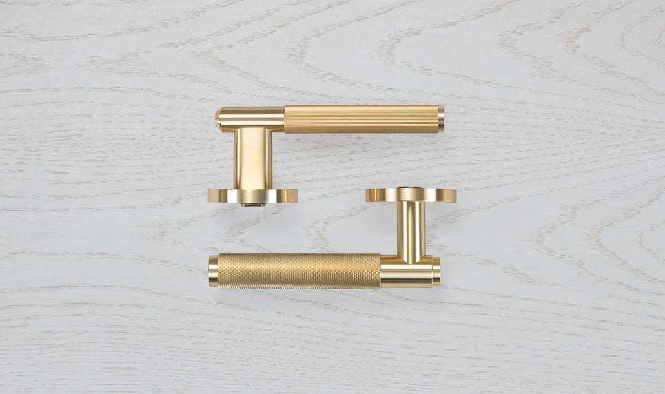 en sats dörrhandtag i mässing med en rå men exklusiv design och linjerat mönster.