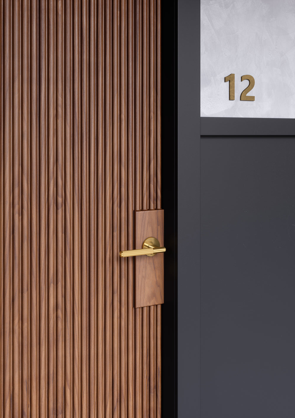 Dörrhandtag i mässing i en rå och exklusiv look med linjerat mönster. Här visas dörrhandtaget monterat på en trädörr.