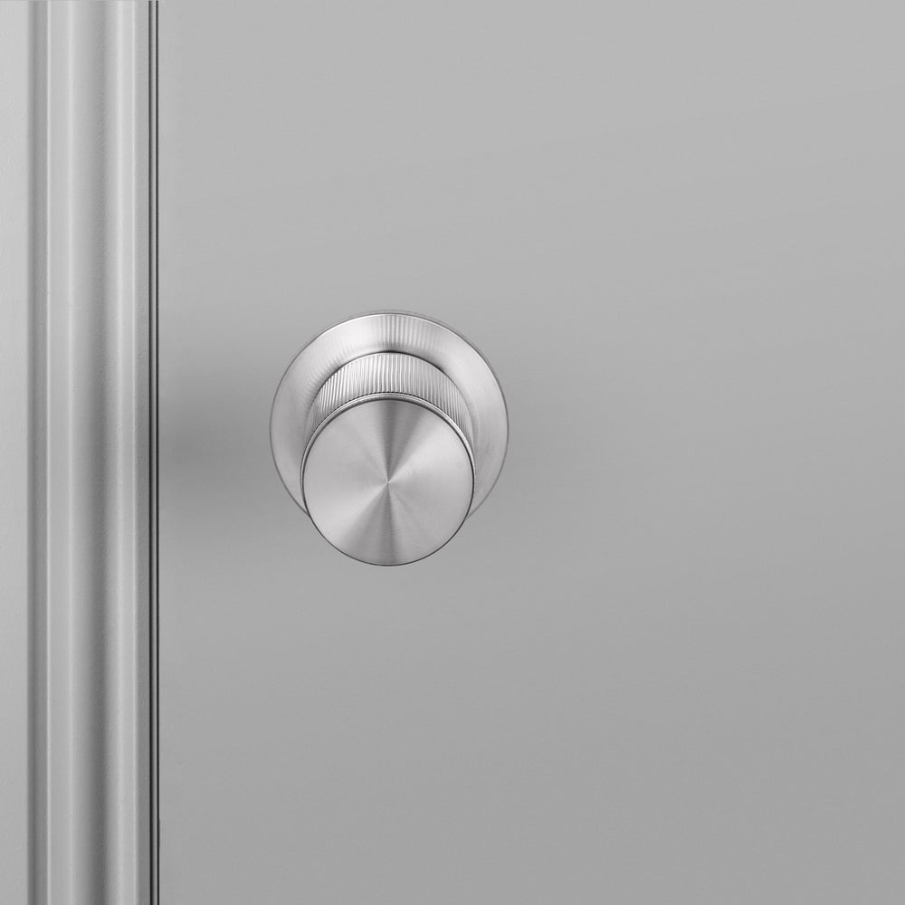 Exklusiv dörrknopp i rostfritt stål med linjerat mönster.