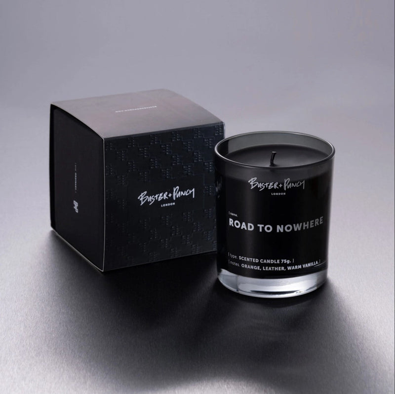 Ask innehållande doftljus av svart vax i rökfärgat glas, mot grå bakgrund.