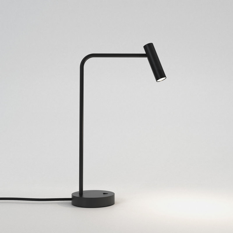 Bordslampa i svart aluminium med böjd hals, rund fot och ett avlångt, rundat, justerbart huvud.