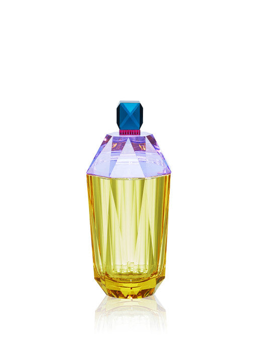 Flaska i gul, lila och blå kristall mot vit bakgrund