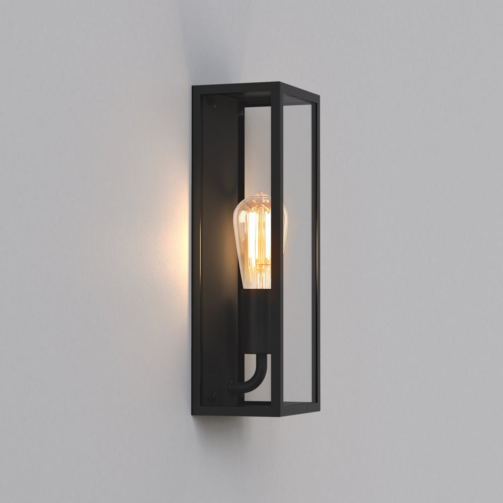 Avlång kantig utomhuslampa med svart stålram och glassidor. Visas här med en glödlampa med synliga glödtrådar.