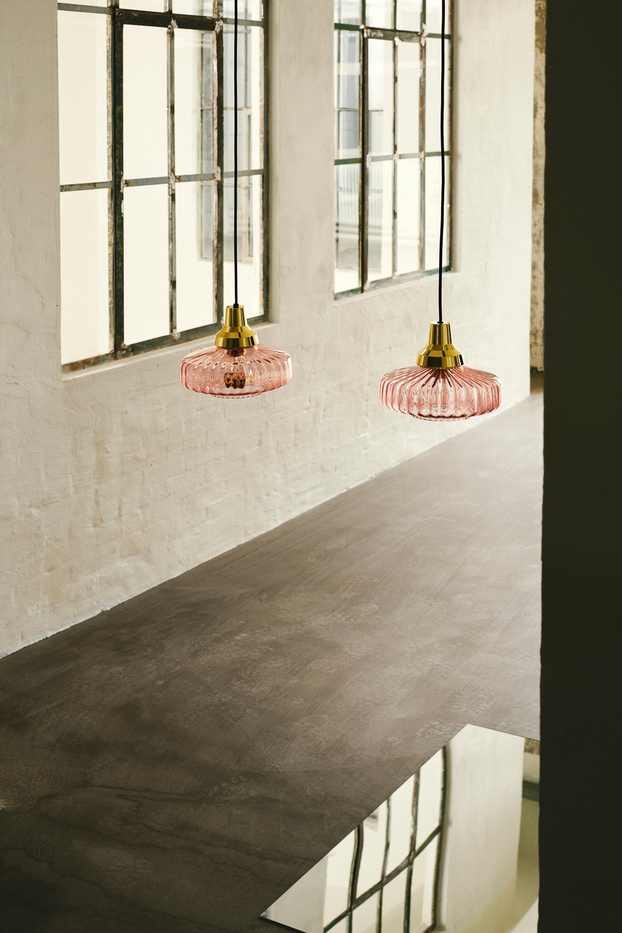 Pendel från Design by Us i rosa glas och med guldfärgad sockel och baksida.
