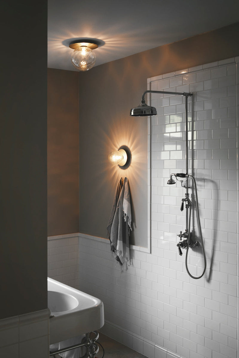 Væglampe samt loftlampe med lampeskærme af klart optikglas og sølvfarvet fatning, på badeværelse