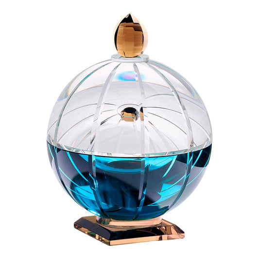 Doftljus i en rund behållare av klar, blå och brun kristall mot vit bakgrund