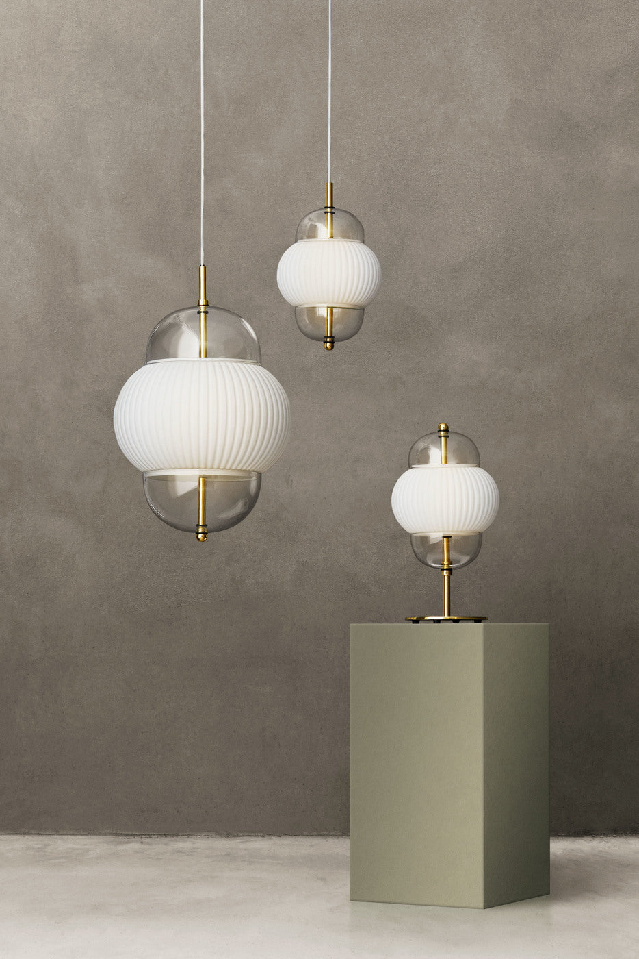 Lampa i klarglas och matt vitt veckat glas. Dessutom har lampan detaljer i mässing och en vit textilkabel.