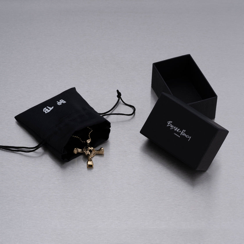 Kartong som innehåller halsband med hänge i form av en dödskalle som samtidigt är en trumnyckel, i mässing